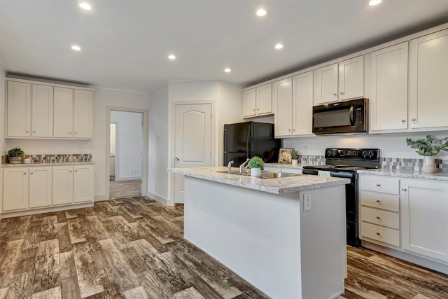 kitchen featuring white cabinetry, an island with sink, black appliances, and wood-type flooring