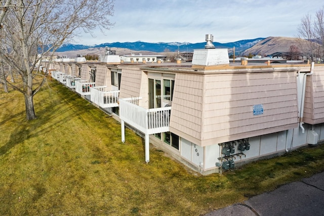 back of property featuring a mountain view and a yard