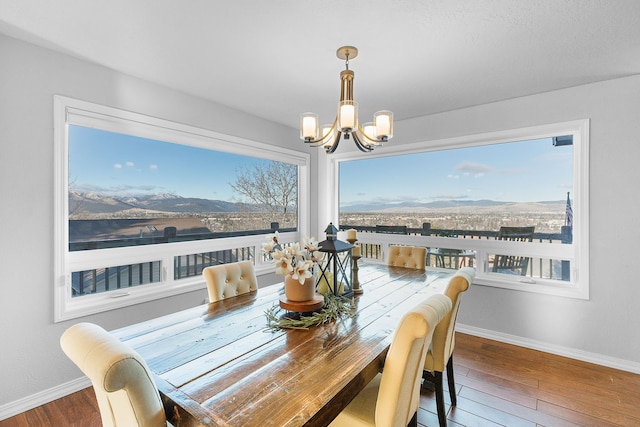 dining room featuring hardwood / wood-style floors, a mountain view, and an inviting chandelier