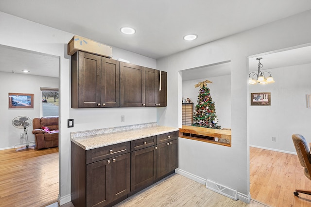 kitchen featuring a notable chandelier, decorative light fixtures, dark brown cabinetry, and light wood-type flooring