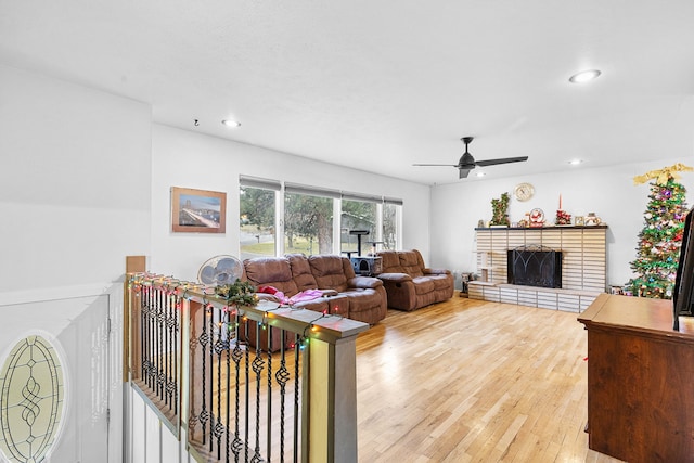 living room with wood-type flooring, a brick fireplace, and ceiling fan