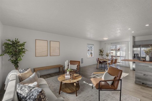 living room with a textured ceiling and light wood-type flooring