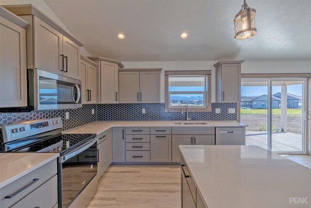 kitchen with sink, stainless steel appliances, backsplash, gray cabinets, and light wood-type flooring