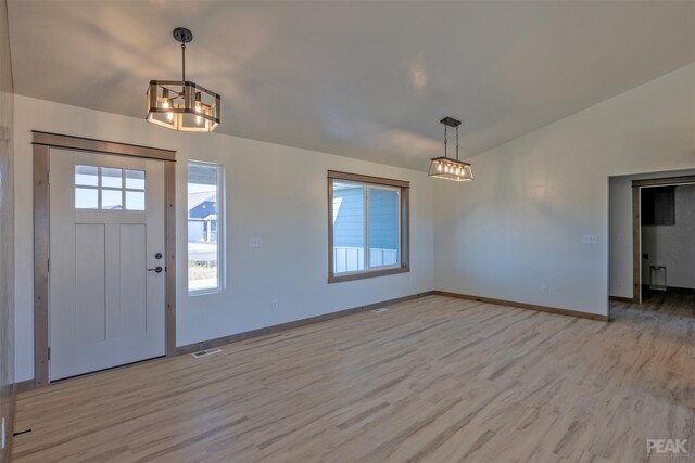 interior space featuring a chandelier, light hardwood / wood-style flooring, and vaulted ceiling