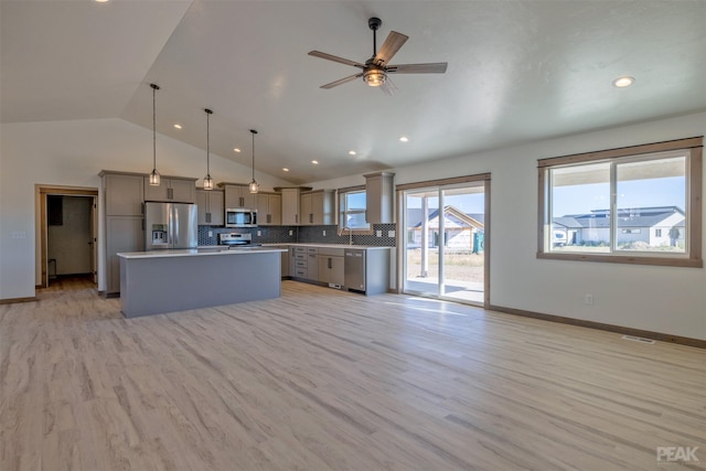 kitchen with appliances with stainless steel finishes, a wealth of natural light, pendant lighting, a kitchen island, and lofted ceiling