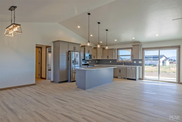 kitchen featuring decorative light fixtures, a kitchen island, light wood-type flooring, and appliances with stainless steel finishes