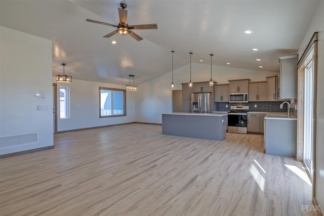 kitchen with stainless steel appliances, vaulted ceiling, hanging light fixtures, and a kitchen island