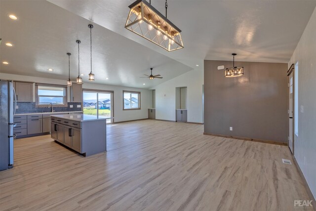 kitchen featuring tasteful backsplash, gray cabinetry, vaulted ceiling, ceiling fan, and decorative light fixtures