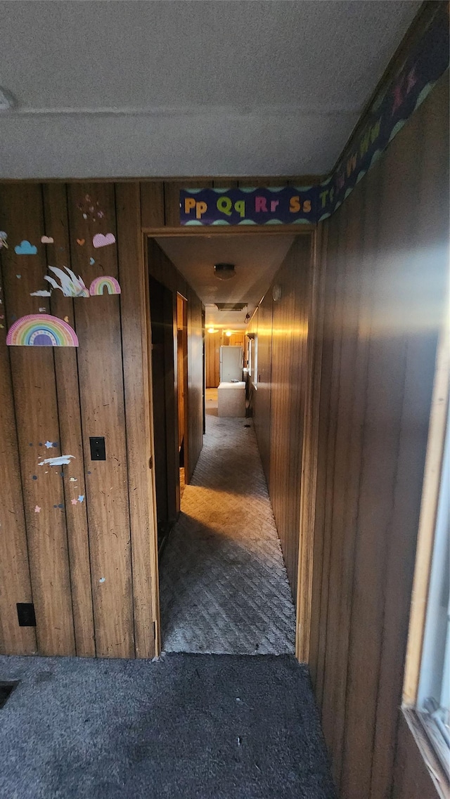 hall featuring dark carpet and wooden walls