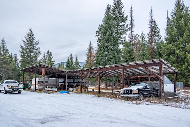 snow covered parking area featuring a carport