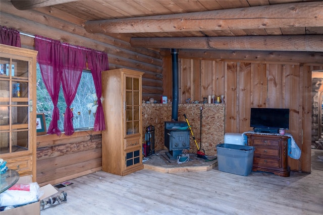 interior space with beamed ceiling, hardwood / wood-style flooring, a wood stove, and wood ceiling