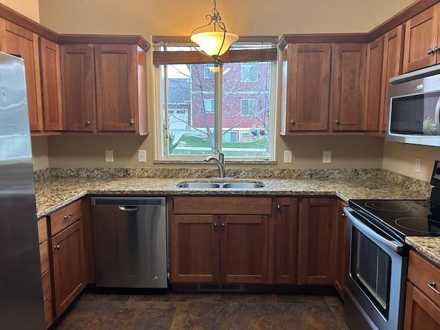 kitchen featuring pendant lighting, light stone counters, sink, and stainless steel appliances