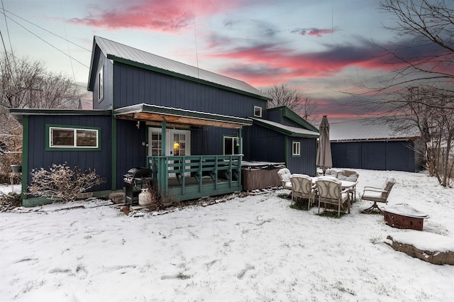 snow covered back of property with a hot tub