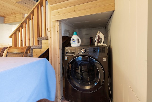 clothes washing area with wood walls and washer / clothes dryer