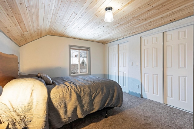 carpeted bedroom featuring vaulted ceiling, multiple closets, and wooden ceiling