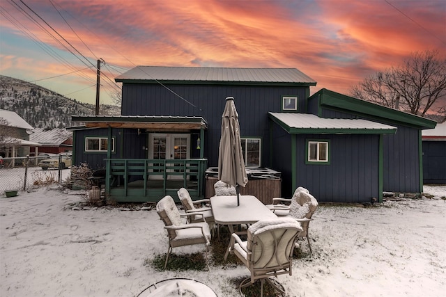 snow covered rear of property featuring a deck with mountain view