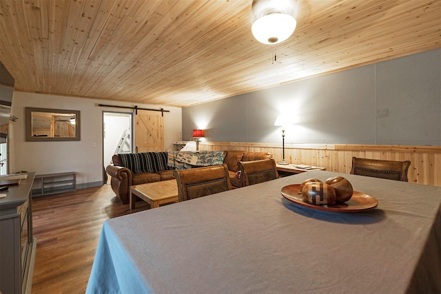 dining room with wood walls, crown molding, hardwood / wood-style flooring, a barn door, and wood ceiling