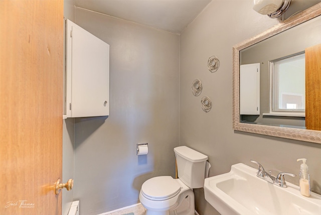 half bath featuring baseboard heating, a sink, and toilet