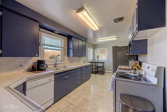 kitchen with tile countertops, visible vents, decorative backsplash, a sink, and white appliances