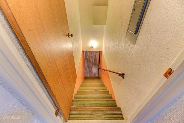 staircase featuring a textured wall and electric panel