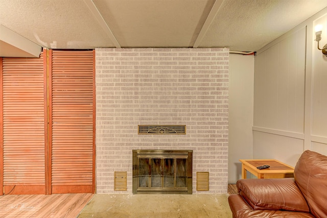 living room featuring a textured ceiling, a brick fireplace, and wood finished floors