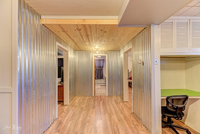 hallway with light wood-style floors, wooden ceiling, and wood walls