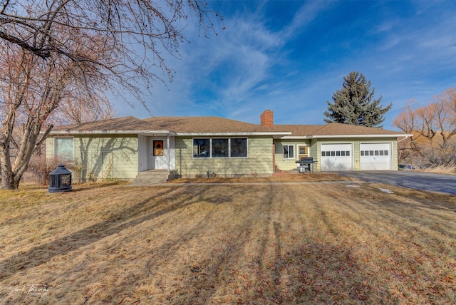 ranch-style house with a garage, driveway, a chimney, and a front lawn