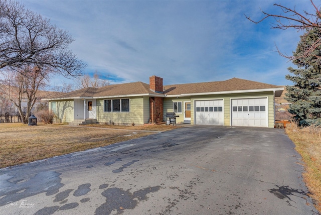 ranch-style home with aphalt driveway, a chimney, and an attached garage