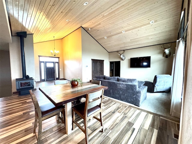 dining area with an inviting chandelier, hardwood / wood-style flooring, wood ceiling, a wood stove, and high vaulted ceiling