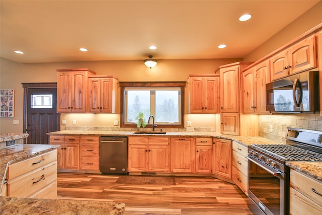 kitchen featuring tasteful backsplash, sink, light wood-type flooring, stainless steel appliances, and light stone counters