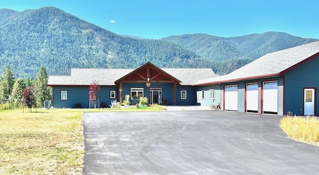 view of front of property featuring a front lawn, a garage, and a mountain view