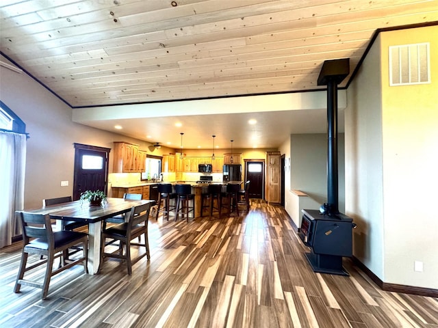 dining space featuring a wood stove, dark hardwood / wood-style flooring, lofted ceiling, and wood ceiling