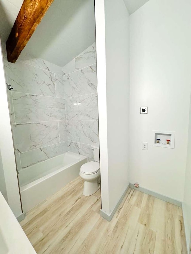 bathroom with hardwood / wood-style flooring, tiled shower / bath combo, and toilet