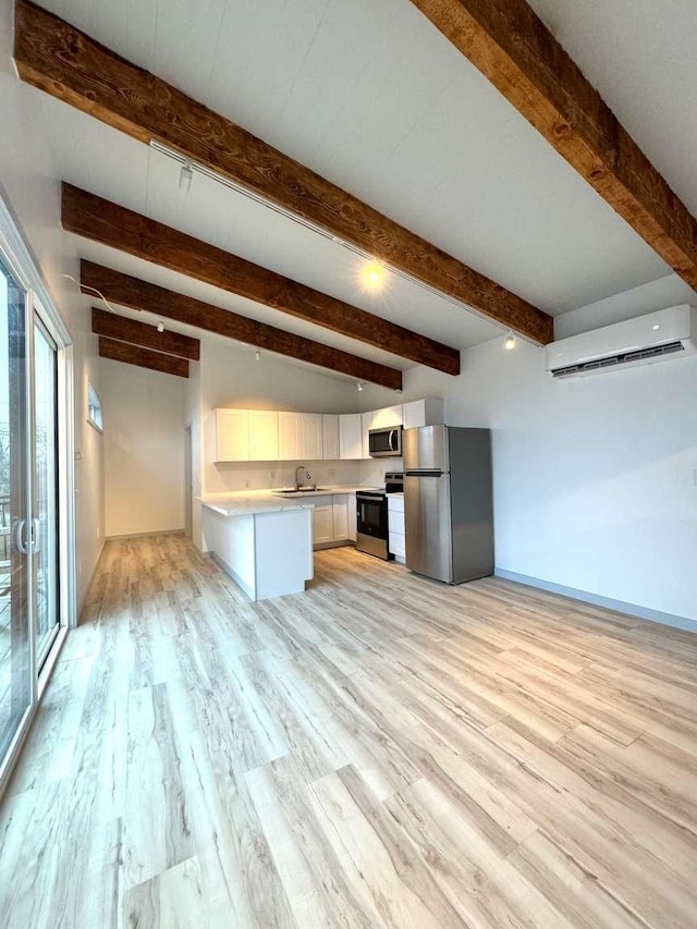 kitchen featuring appliances with stainless steel finishes, beam ceiling, an AC wall unit, white cabinets, and light hardwood / wood-style floors