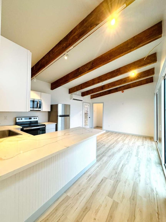 kitchen with kitchen peninsula, appliances with stainless steel finishes, a wall mounted AC, light hardwood / wood-style flooring, and white cabinetry