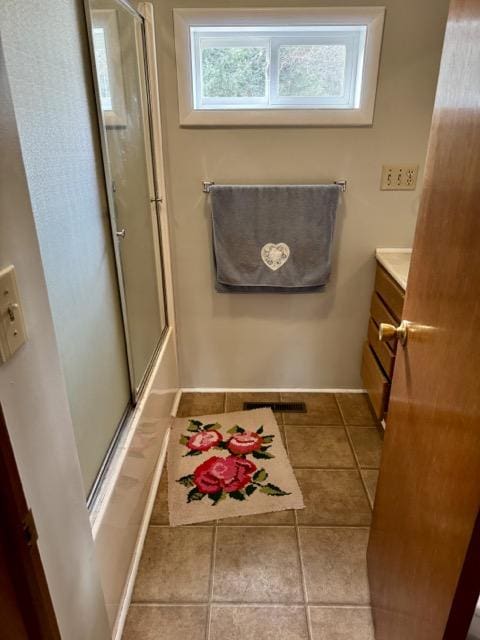 bathroom with tile patterned floors, vanity, and bath / shower combo with glass door