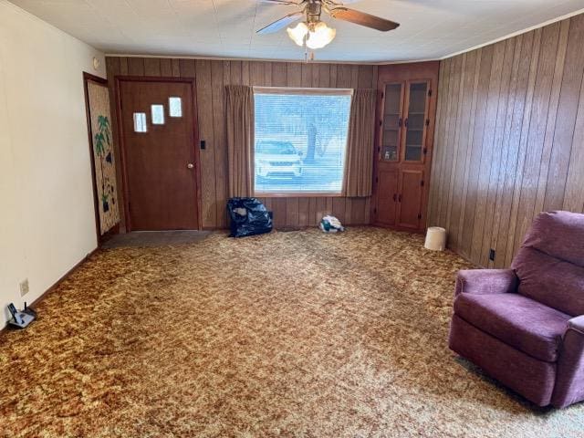 interior space with carpet, ceiling fan, and wood walls