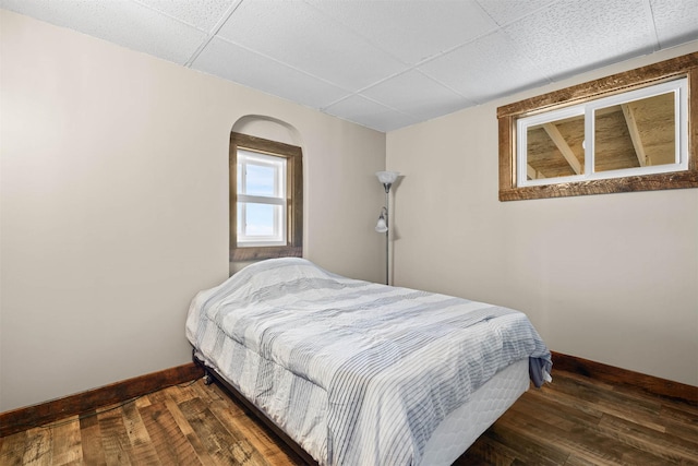 bedroom featuring a paneled ceiling and dark wood-type flooring