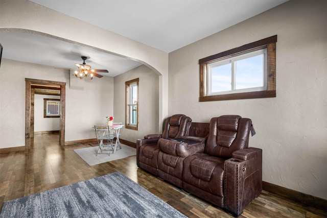 living room with a healthy amount of sunlight, ceiling fan, and dark wood-type flooring