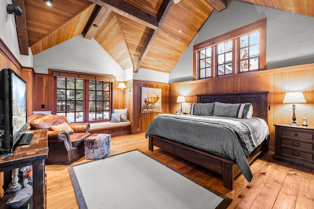 bedroom with beamed ceiling, wood ceiling, wooden walls, and light hardwood / wood-style flooring