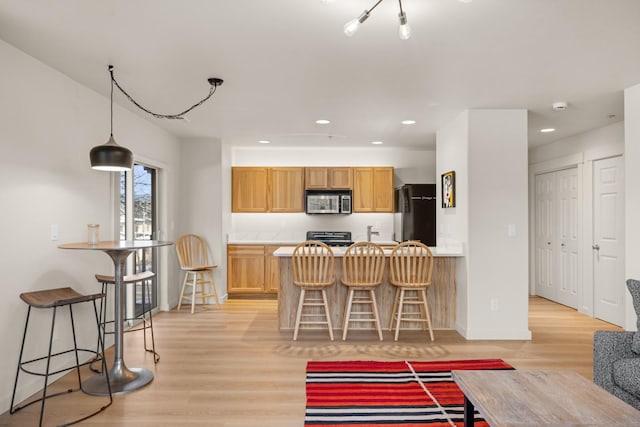 kitchen with a breakfast bar, light wood-type flooring, and fridge