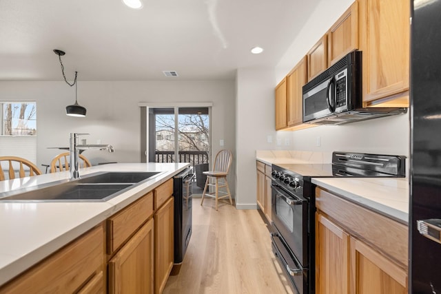 kitchen featuring hanging light fixtures, sink, black appliances, and light hardwood / wood-style floors