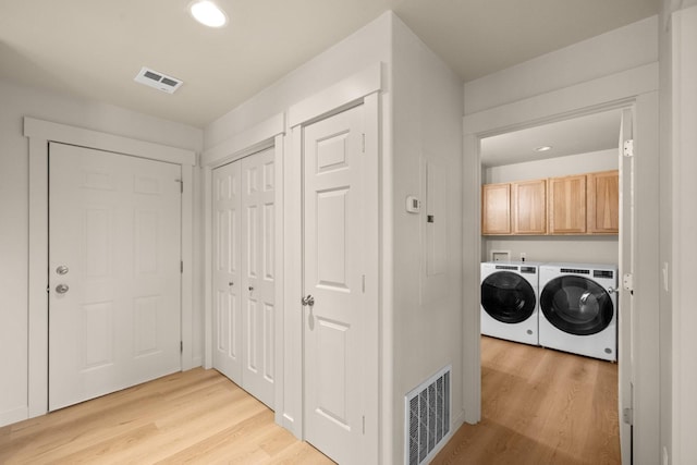 clothes washing area featuring cabinets, separate washer and dryer, and light hardwood / wood-style flooring