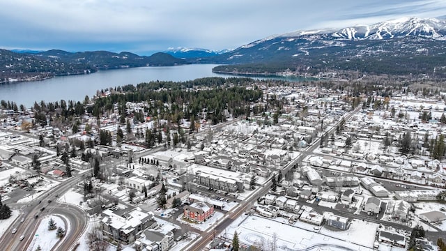 snowy aerial view featuring a water and mountain view