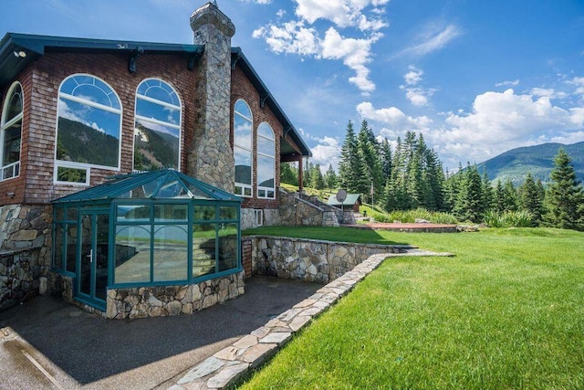 rear view of house featuring a mountain view, a yard, and an outbuilding