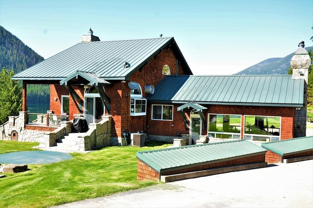 back of property featuring a lawn, a mountain view, and central AC