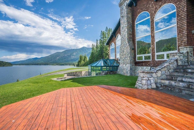 deck with a lanai, a water and mountain view, and a lawn