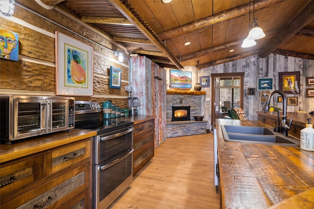 kitchen with sink, wooden counters, wooden ceiling, light hardwood / wood-style floors, and range with two ovens