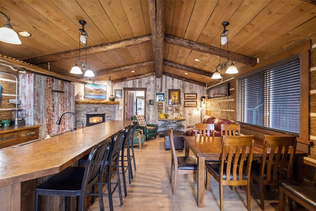 dining space featuring lofted ceiling with beams, a fireplace, light wood-type flooring, and wooden ceiling