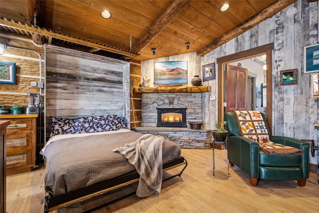 bedroom with wood ceiling, light hardwood / wood-style flooring, a stone fireplace, and wooden walls